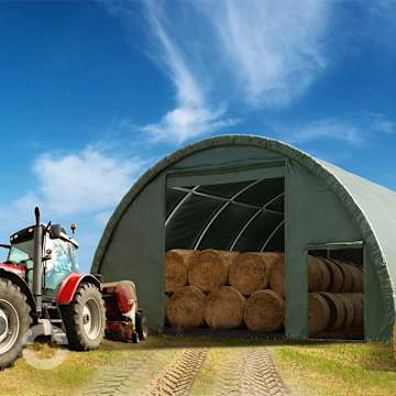 Rundbogenhalle zur Lagerung von Heuballen und Brennholz, davor ein Traktor mit Frontlader beim Be- und Entladen.