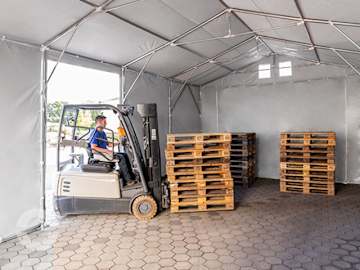 Lagerzelt mit Gabelstapler und Holzpaletten als mobile Lagerhalle für Industrie und Gewerbe.
