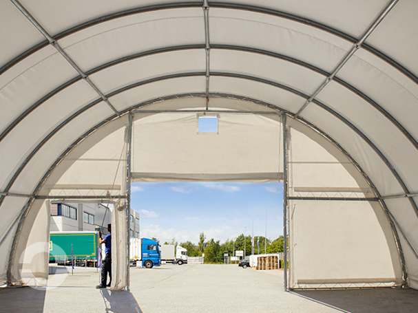 Innenansicht einer selbsttragenden Rundbogenhalle mit freier Spannweite und großem Einfahrtstor.