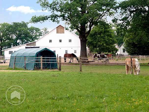 Carpa para forraje delante de un establo