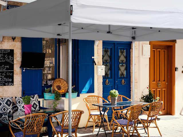 Outdoor café seating area sheltered under a 4x4 pop up gazebo on a bright day